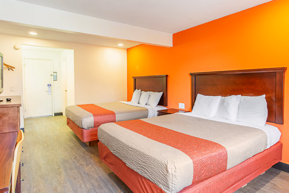Spacious room with two queen beds, desk, television, and vanity