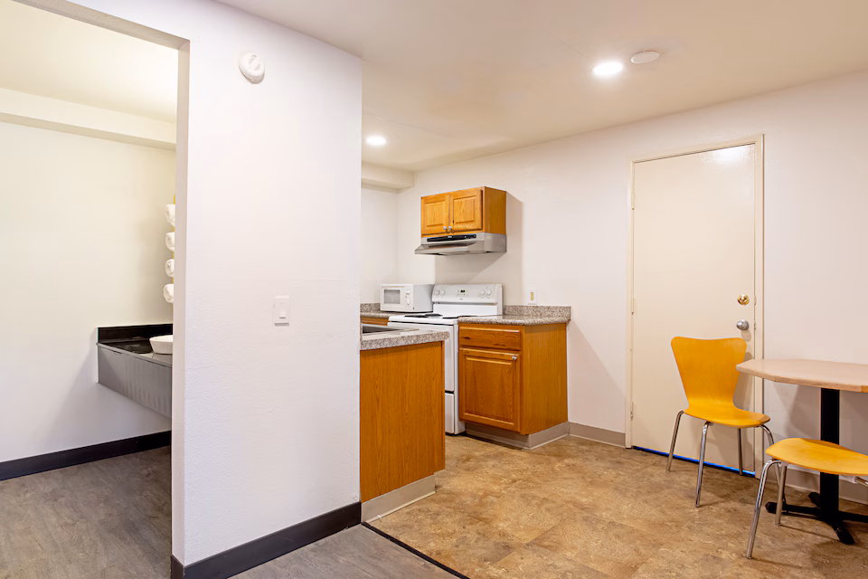 In-room kitchenette with stove, microwave, cabinets, and dining table