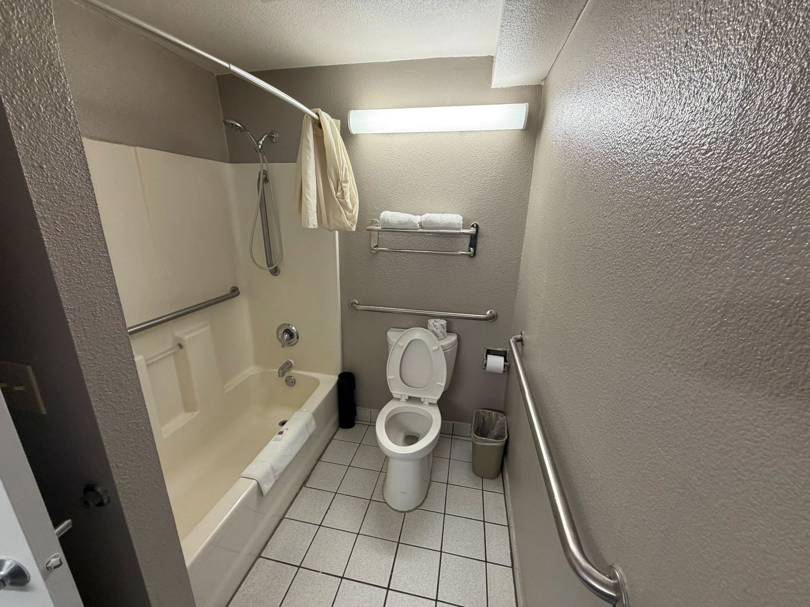 Mobility-accessible bathroom with grab bars and bathtub