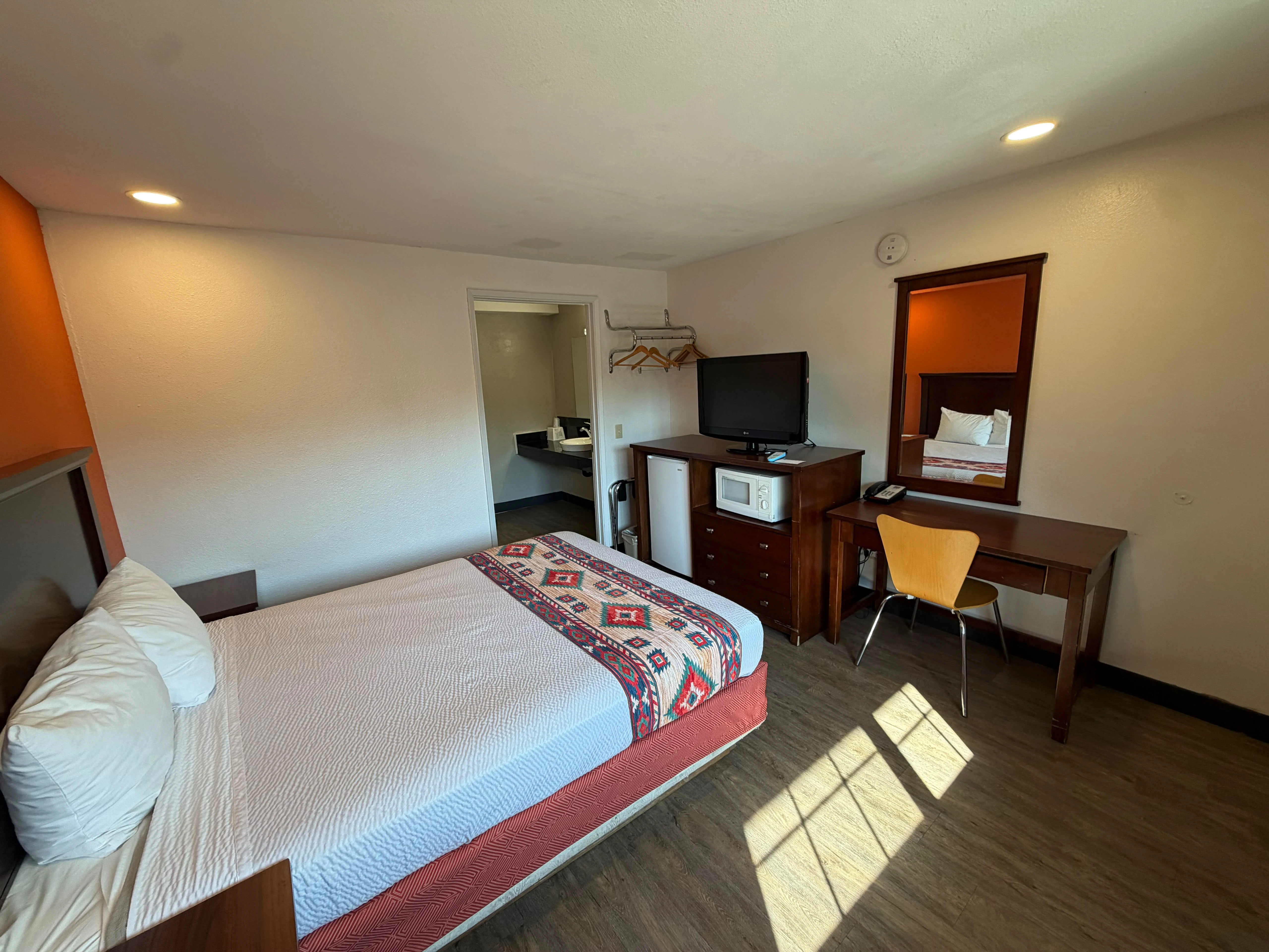 Queen room with desk, television, microwave, and refrigerator