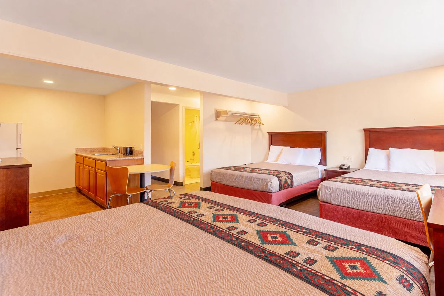 Large guest room with three queen beds, a kitchenette, and Southwestern-style bed runners