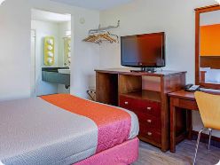 Queen guest room with desk, television, and vanity