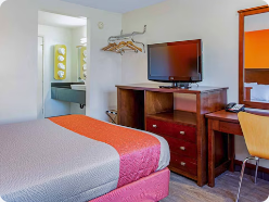Queen guest room with desk, television, and vanity